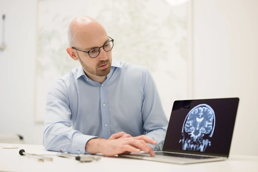 Dr. Florian Blauensteiner Neurologe in Wien zeigt Analyse am Laptop